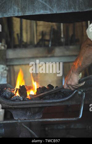 Close up de flammes avec homme forgeron forge au travail des formes de décisions dans son atelier de forgeron, Hillsboro, Wisconsin, USA. Banque D'Images