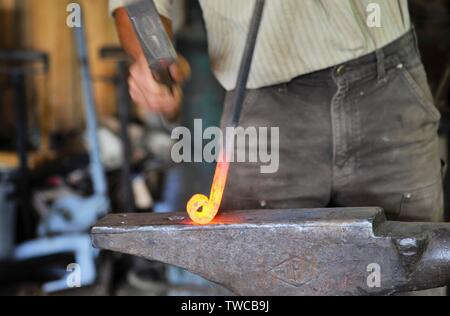 Close up of male avec un marteau de forgeron forge battre red-hot rod de métal sur l'enclume, jetant des étincelles tout en façonnant le métal, Hillsboro, Wisconsin, USA. Banque D'Images