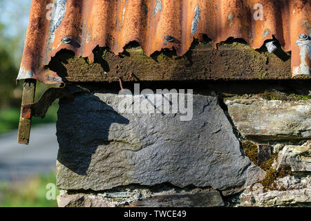 L'article de l'ancienne grange sur croft,avec toit en tôle ondulée rouillée en décomposition et mur de pierre brute artistique donnant. Lochcarron village, montagnes de l'Ecosse Banque D'Images