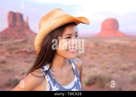 Cowgirl femme heureuse portrait in Monument Valley wearing cowboy hat. Beautiful smiling young woman outdoors multiraciale, Arizona, Utah, USA. Banque D'Images