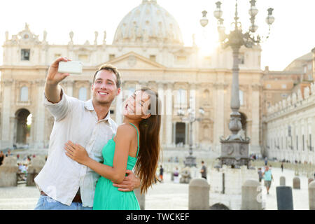 Couple de touristes par la Cité du Vatican et la Basilique Saint Pierre Église de Rome. Happy travel la femme et l'homme de prendre photo sur photo selfies lune de miel romantique en Italie. Banque D'Images