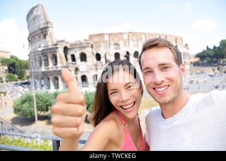 Voyage Romantique - selfies par couple Colisée, Rome, Italie. Les amoureux heureux sur vos visites de miel s'amusant en face de Colisée. Woman giving Thumbs up in tourism travel concept. Banque D'Images