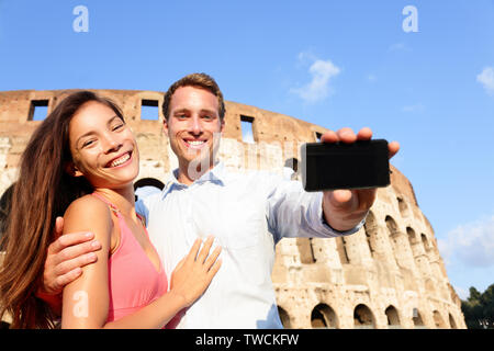 Smartphone montrant deux à Rome par le Colisée en Italie. Les amoureux heureux en lune de miel visites Colisée. Amour et travel concept avec couple multiracial. Banque D'Images