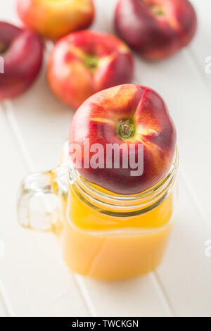 Les nectarines mûres et verre de jus de télévision sur tableau blanc. Banque D'Images