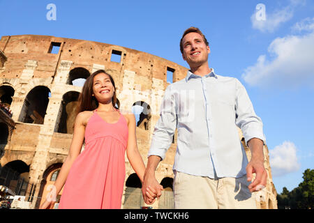 Couple à Rome par Colosseum walking holding hands en Italie. Les amoureux heureux sur vos visites de miel s'amusant en face de Coliseum. Amour et travel concept avec couple multiracial. Banque D'Images