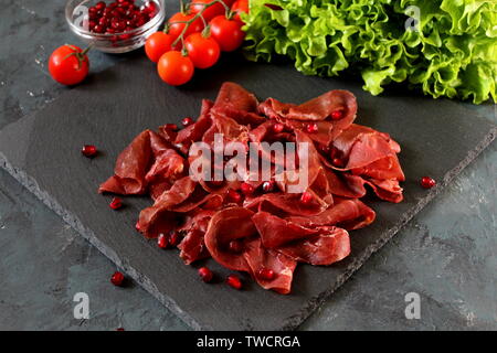 Salé et séché à l'air italien boeuf bresaola émincée et fond en pierre. Vue d'en haut. Copier l'espace. Fer à repasser sur l'aliment. Banque D'Images