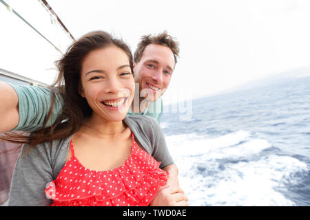 Bateau de croisière couple taking self portrait selfies photo romantique. Heureux amants, la femme et l'homme en voyage à voyage sur mer océan ouvert bénéficiant d'amour. Young Asian Woman and Caucasian man. Banque D'Images