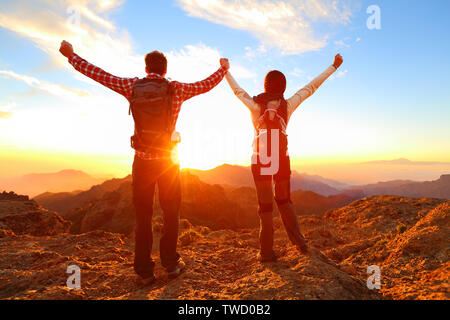 La liberté - heureux couple cheering et célébrer. Randonnées man and woman raising arms excité dans la célébration à l'extérieur. Les randonneurs au coucher du soleil en profitant de la montagne montagne sommet et succès. Banque D'Images