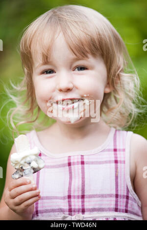 Smiling little girl avec visage souillé et la crème glacée à la main vue rapprochée Banque D'Images