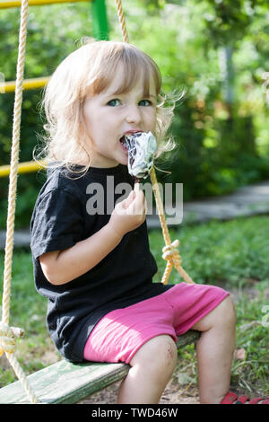 Little girl eating ice cream sur fond de plein air d'été Banque D'Images