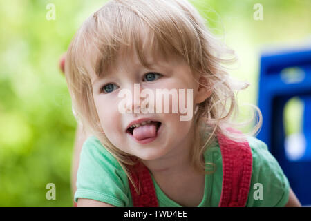 Petit enfant caucasian girl face closeup sur fond de plein air d'été vert Banque D'Images