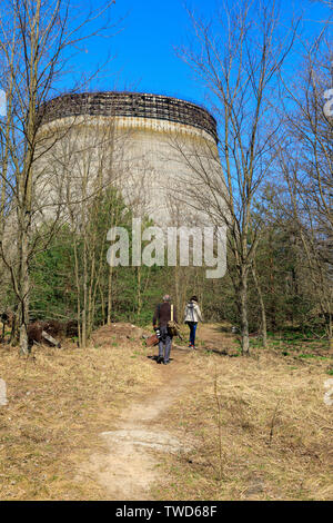 L'Europe de l'Est, l'Ukraine, Pripyat, Tchernobyl. Les touristes à marcher le long chemin vers la tour de refroidissement non fini pour les réacteurs 5 et 6 qui n'ont jamais été complet Banque D'Images