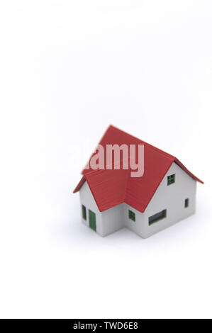 Une petite maison traditionnelle avec toit rouge sur une surface blanche et de l'espace pour ajouter d'autres éléments graphiques, ainsi que des textes. Banque D'Images