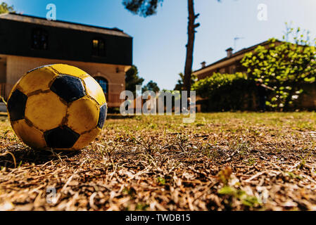 Close-up d'un vieux ballon de football porté dans la cour d'une maison. Banque D'Images