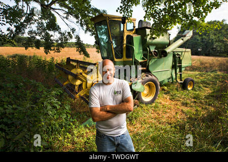 États-unis - 17 juillet 2017 : Farmer Trent Tebbe, pose pour une photo devant son vintage des années 1960 Moissonneuse-batteuse John Deere dans un champ de seigle à Morven Park. Banque D'Images