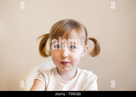 Peu surpris kid Caucasian girl avec les yeux grand ouvert closeup portrait mignon sur fond uni Banque D'Images