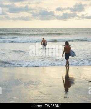 L'ÎLE DE BALI, INDONÉSIE - 12 février 2017 : les hommes avec des planches au coucher du soleil plage Océan surf session pour aller Banque D'Images