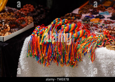 Pendentifs colorés sur l'écran de vente d'un un marché. Bijoux, accessoires, le bouddhisme, l'artisanat, l'art, fait main, du fil, de fils, de couleurs, de la laine, tricots. Banque D'Images