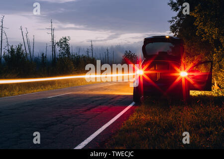 Voiture avec les phares sur le côté de la route Banque D'Images