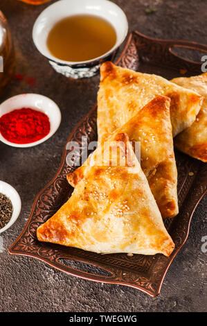 De l'est fraîchement cuits sur un plateau vintage samsa Close up.pâtisserie orientale traditionnelle - samsa rempli de viande. Banque D'Images