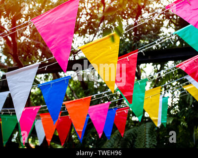 Festival haut en couleurs drapeaux suspendus dans le jardin. Belle couleur de décoration drapeaux triangle parti sur fond d'arbres. Banque D'Images