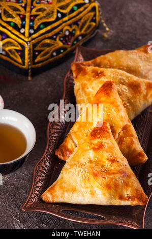 De l'est fraîchement cuits sur un plateau vintage samsa Close up.pâtisserie orientale traditionnelle - samsa rempli de viande. Banque D'Images