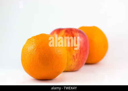 Les oranges et les pommes dans la rangée sur fond blanc. Banque D'Images