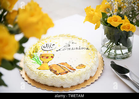 Première communion concept, belle composition : doux gâteau blanc et jaune avec texte en italien : première communion, avec des roses jaunes sur un wh Banque D'Images