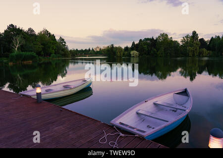 Bateaux en bois sur un lac calme appelé Csonakazo à Szombathely Hongrie lac au crépuscule après le coucher du soleil Banque D'Images