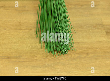 Les tiges de plastique vert long balai sur le plancher en bois en arrière-plan avec la texture. Banque D'Images