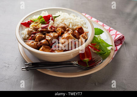 Bol contenant un assortiment de riz et de goulasch et plaque de maintien des feuilles d'herbe à côté de serviette sur la table gris Banque D'Images