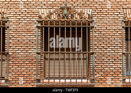 Fenêtre avec une grille métallique sur un mur de briques Banque D'Images