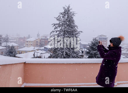 Woman outdoors sitting on taking photograph of snowy vue panoramique durant tempête à Avezzano région Vénétie en Italie. Banque D'Images