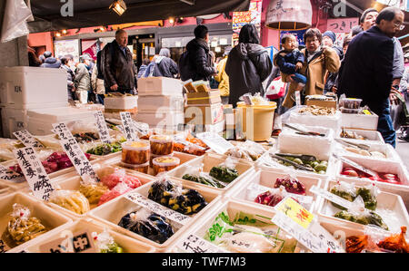 Affichage de la nourriture fraîche et des gens qui marchent à travers dans le marché aux poissons de Tsukiji à Tokyo au Japon. Banque D'Images