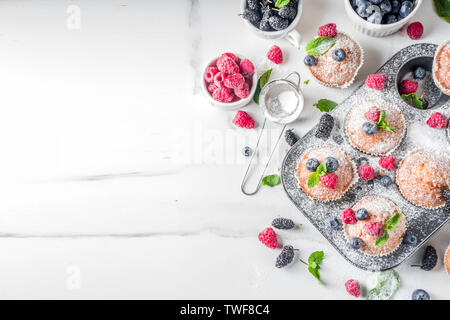 Muffins à la vanille ou des petits gâteaux avec les baies fraîches sur fond de marbre blanc Banque D'Images