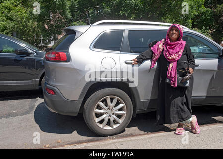 Une femme musulmane dans un hijab attend de prendre un enfant en dehors de P.S. 69 à Jackson Heights, Queens, New York. Banque D'Images