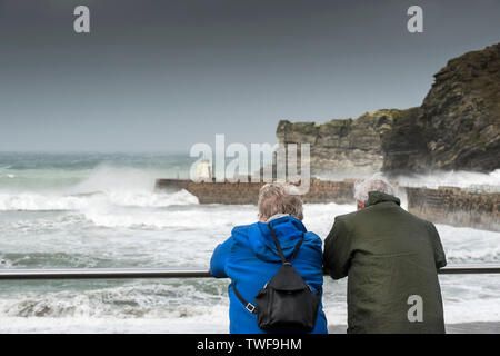 A mature couple regardant la mer rugueuse à Portreath à Cornwall. Banque D'Images