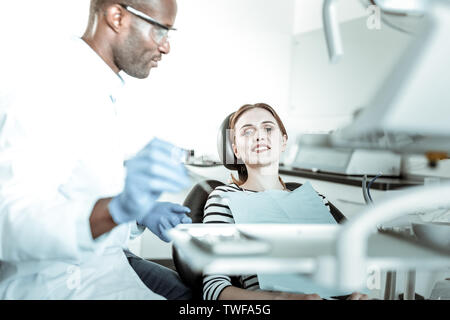 Outils stérilisés. Jolie femme souriante ayant problème avec ses dents et la visite de dentiste à cause de cela Banque D'Images