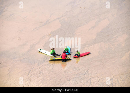 Les jeunes vacanciers, à l'écoute de leur instructeur de surf pendant une leçon de surf sur la grande plage de l'Ouest à Newquay en Cornouailles. Banque D'Images