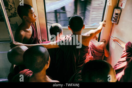 Les jeunes moines bouddhistes sont à la recherche d'un train en mouvement occupé à Yangon. Banque D'Images