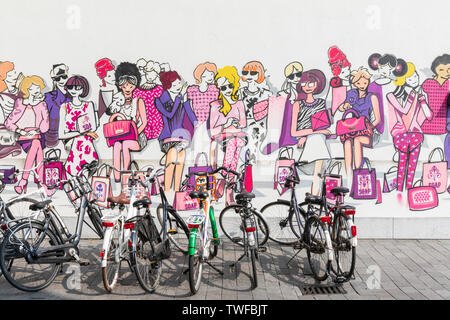 Bicyclettes garées en face de street art qui illustrent un groupe de femmes à la mode. Banque D'Images