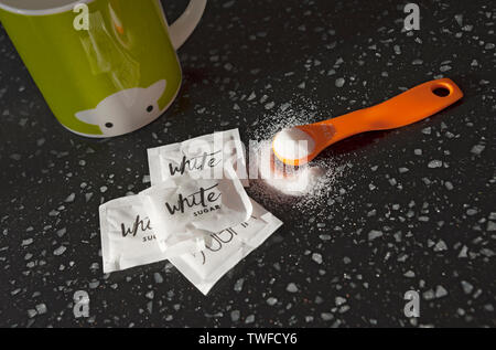 Close up of cuillerée de sucre blanc et sachets de sucre. Banque D'Images