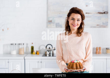 Smiling happy woman holding plaque avec pain de Pâques dans la cuisine Banque D'Images