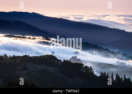 Vue du coucher de brouillard et les nuages couvrant les creux dans la Santa Cruz Mountains ; mer de nuages et ciel rose illuminée par le soleil couchant visible dans la b Banque D'Images