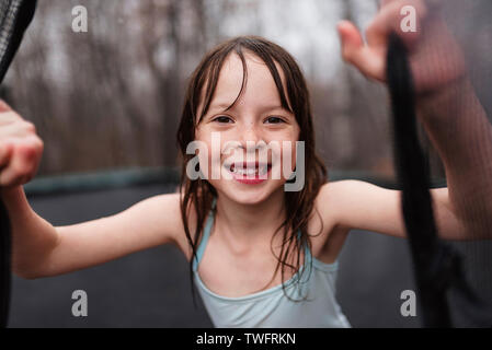 Smiling girl jouant sur un trampoline dans la pluie, États-Unis Banque D'Images