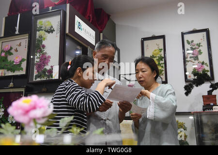 (190620) -- SHANGHAI, le 20 juin 2019 (Xinhua) -- Dai Chunfu (C) communique avec deux passionnés de Yangzhou, Jiangsu Province de Chine orientale, le 18 juin 2019. Vigne, chocolat ou Akebia quinata, fait un grand ingrédient d'artisanat divers y compris les fleurs artificielles. La fleur de décision est complexe, car il contient une série de procédures, y compris le blanchissement, coller, façonner et la teinture. Pourtant, les fleurs artificielles faits de ces arbustes sont vives et ont une grande valeur. En 2007, la fleur de décisions techniques ont été répertoriées comme patrimoine culturel immatériel de la province de Jiangsu. Dai Chunfu, 79, a été un dans Banque D'Images