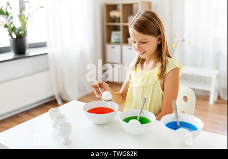 Fille oeufs de pâques par colorant liquide à la maison Banque D'Images