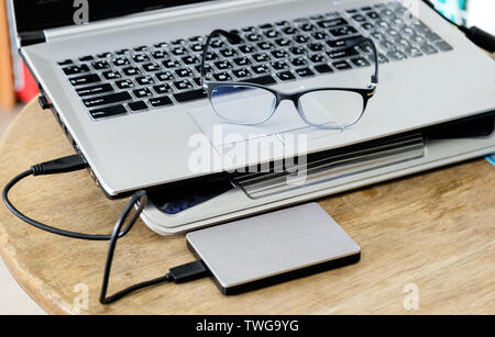 Clavier ordinateur portable moderne gris gris noir avec disque dur et spectacles sur table en bois Banque D'Images