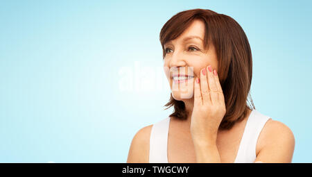 Portrait of smiling senior woman touching her face Banque D'Images