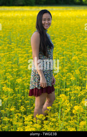 Une belle adolescente regarde vers la caméra et sourit tout en se tenant dans un champ de jaune à Fort Wayne, Indiana, USA. Banque D'Images